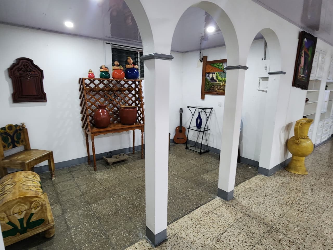 Corredor con arcos blancos, cerámica artesanal y guitarra