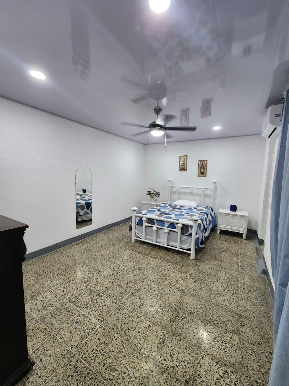 Vista amplia de la habitación con cómoda de madera y cortinas