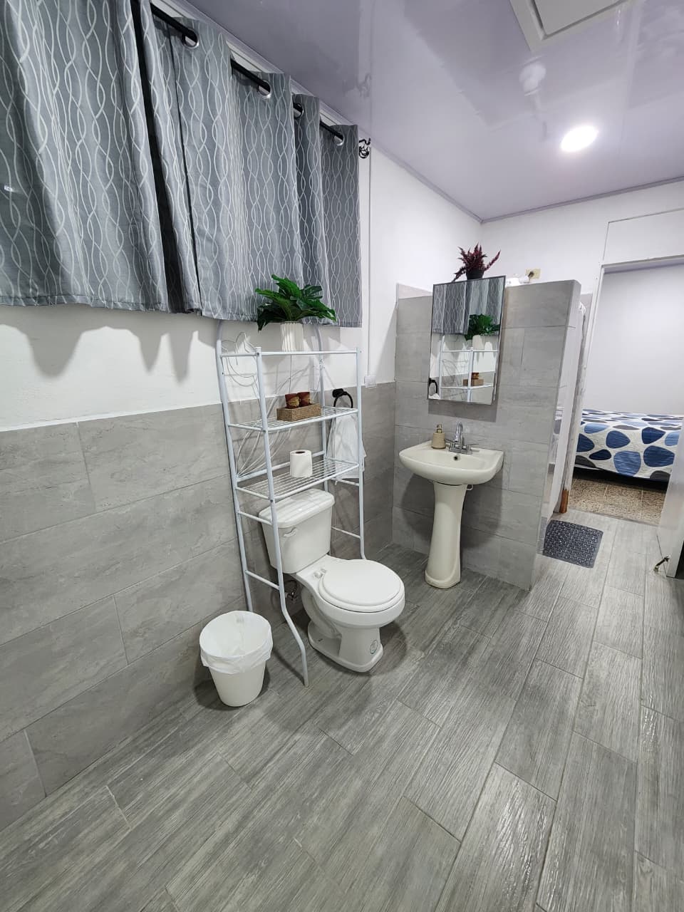 Baño privado con inodoro, lavamanos, espejo y repisas