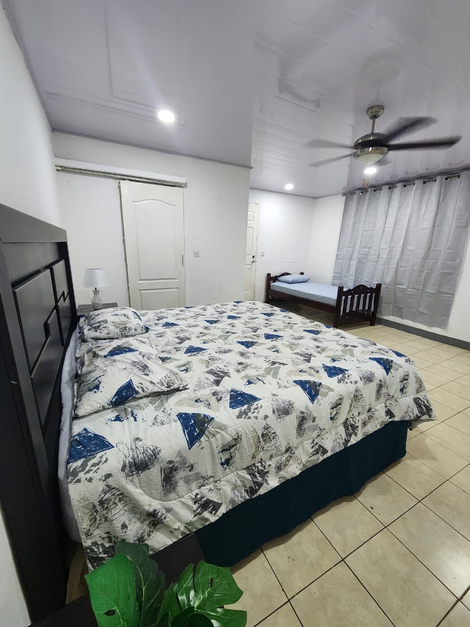 Habitación con cama King e individual, aire acondicionado y ventilador de techo