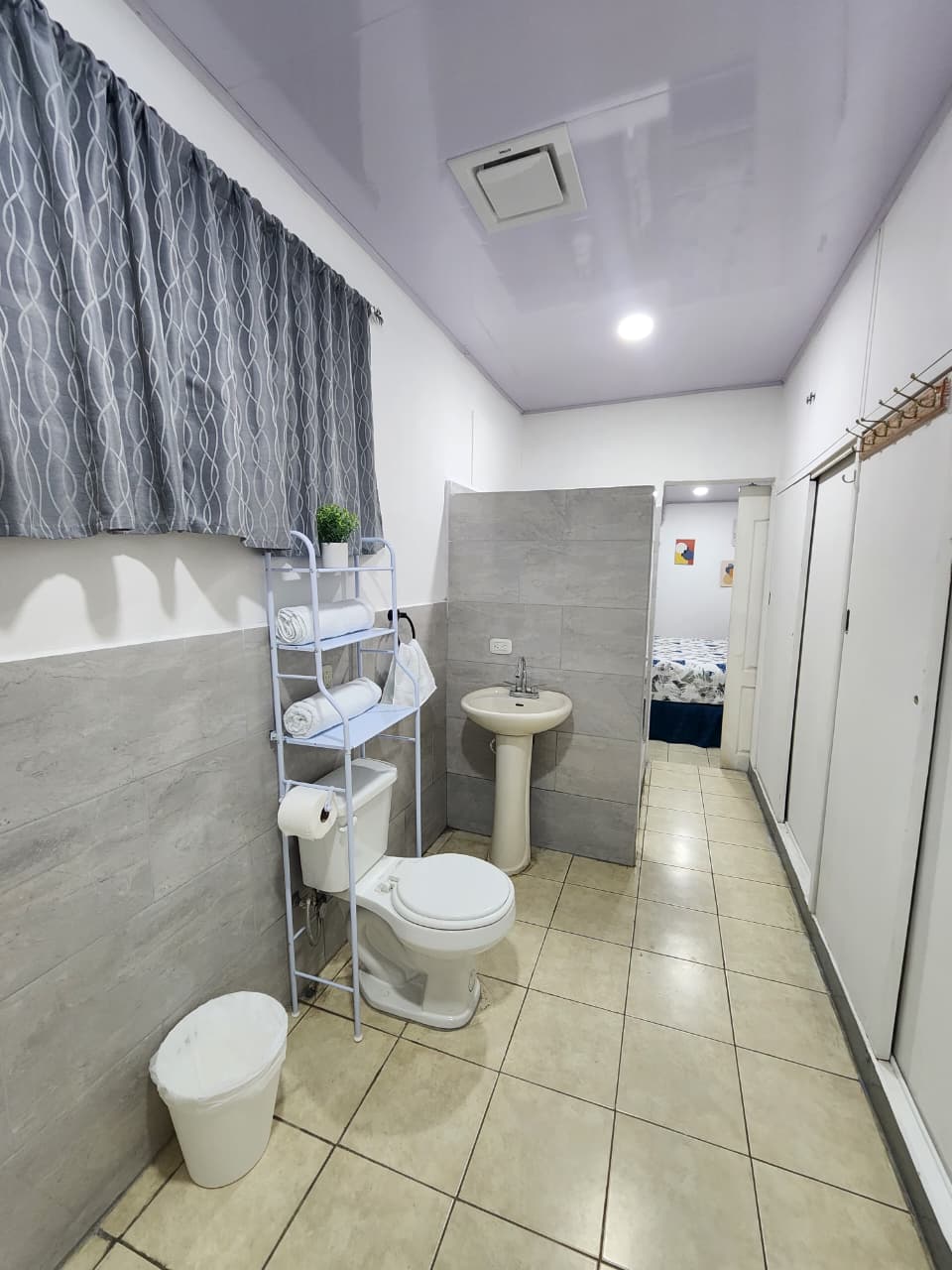Baño privado con inodoro, lavamanos, espejo y repisas